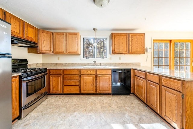 kitchen with brown cabinetry, a peninsula, stainless steel appliances, under cabinet range hood, and a sink