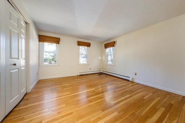 spare room with plenty of natural light, light wood-style flooring, and baseboard heating