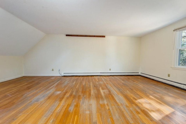 additional living space featuring vaulted ceiling, baseboard heating, and light wood-type flooring