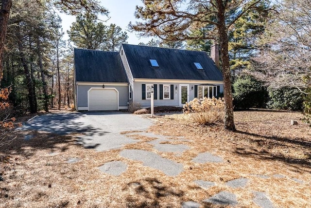 cape cod house with a garage, driveway, and a chimney