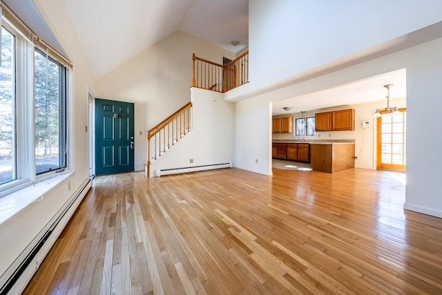 foyer entrance with a baseboard heating unit, light wood-type flooring, and stairway