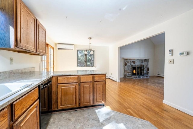 kitchen featuring light wood finished floors, black dishwasher, brown cabinetry, a wall mounted air conditioner, and a peninsula