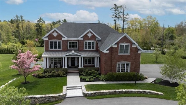 view of front of house featuring a porch, brick siding, and a front lawn