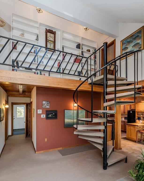 stairway with a towering ceiling, baseboards, and carpet floors