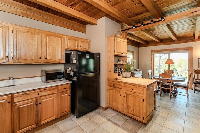 kitchen featuring stainless steel microwave, beamed ceiling, light tile patterned floors, wood ceiling, and freestanding refrigerator