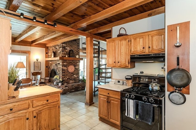 kitchen with beam ceiling, under cabinet range hood, light tile patterned floors, black gas stove, and wood ceiling