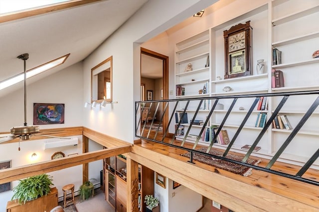 hallway with lofted ceiling, stairway, a wall unit AC, and built in shelves