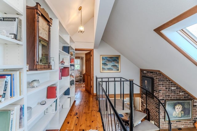 interior space with light wood finished floors, an upstairs landing, and vaulted ceiling