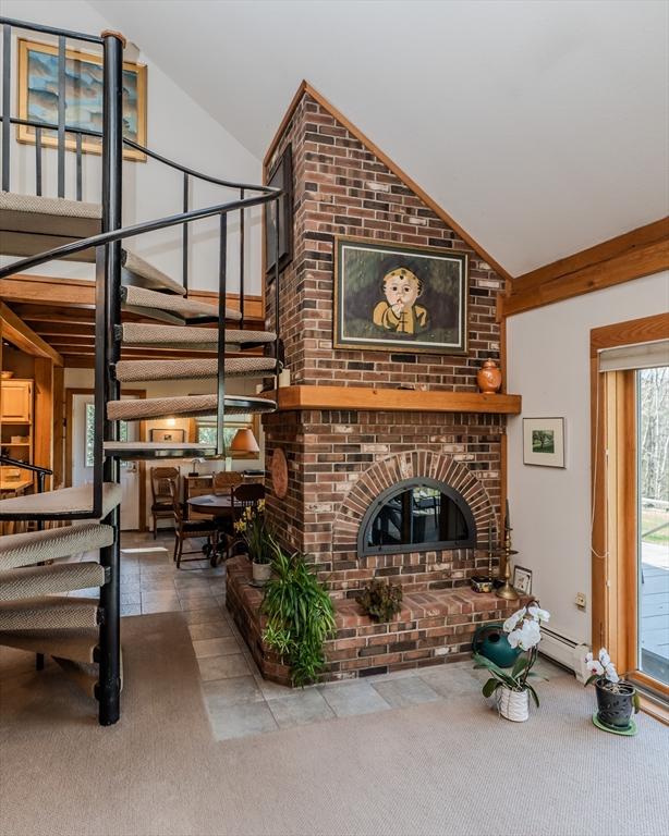 carpeted living area with tile patterned flooring, high vaulted ceiling, stairway, and a baseboard radiator
