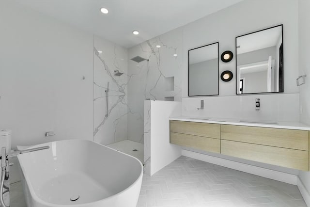 full bathroom featuring double vanity, recessed lighting, a freestanding bath, a sink, and a marble finish shower