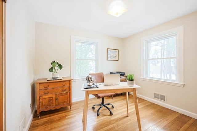 office space featuring light wood-style flooring, visible vents, and baseboards