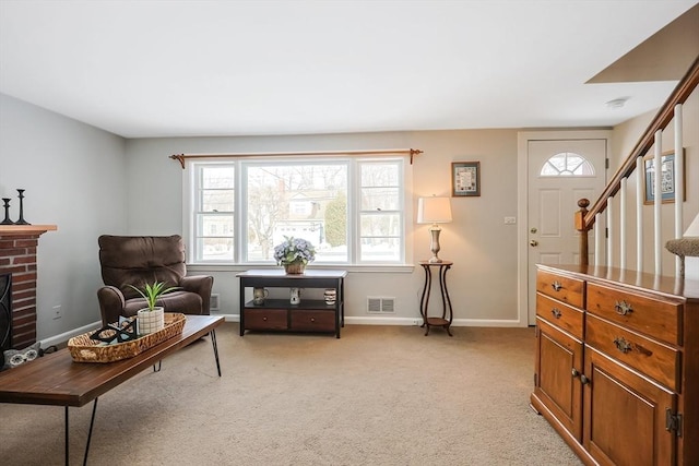 sitting room featuring visible vents, baseboards, light colored carpet, stairs, and a fireplace