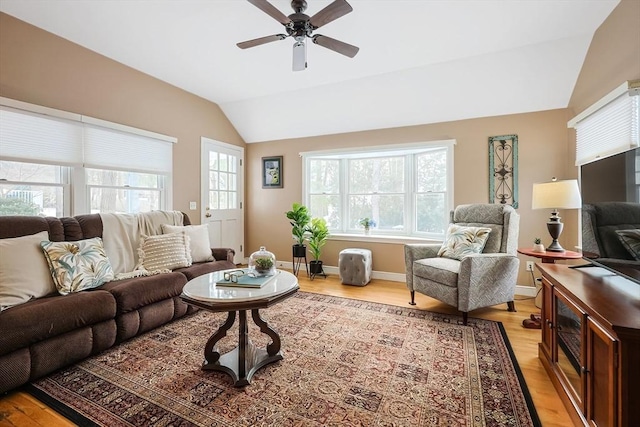 living area with vaulted ceiling, baseboards, a ceiling fan, and light wood-style floors