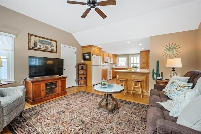 living area featuring lofted ceiling, light wood-style floors, and a ceiling fan