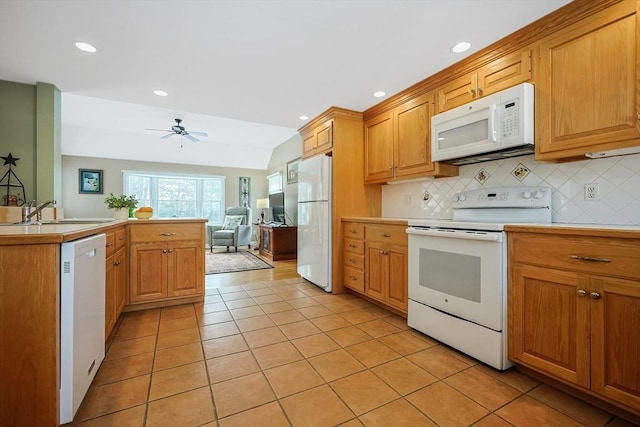 kitchen featuring light countertops, white appliances, backsplash, and a sink