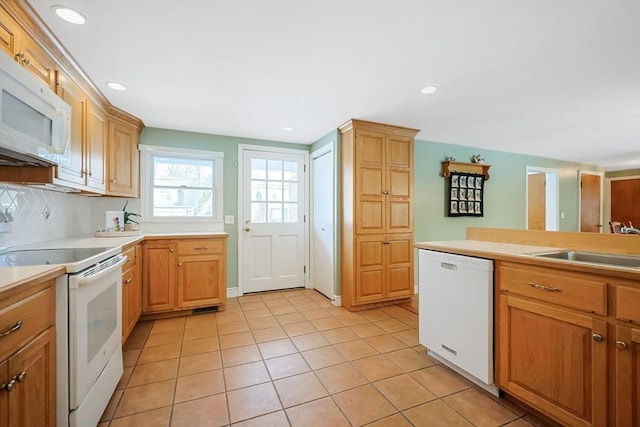 kitchen with light tile patterned floors, recessed lighting, white appliances, a sink, and light countertops