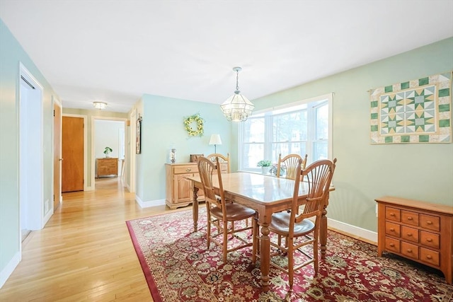 dining space with a notable chandelier, light wood-type flooring, and baseboards