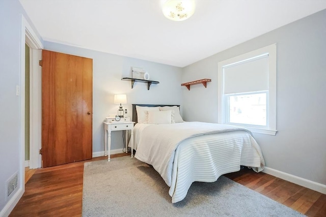 bedroom featuring baseboards, visible vents, and wood finished floors