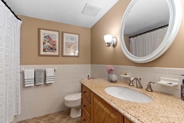 bathroom featuring tile patterned flooring, vanity, tile walls, and toilet