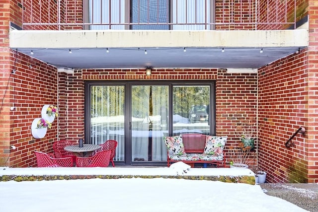 snow covered property entrance featuring a balcony