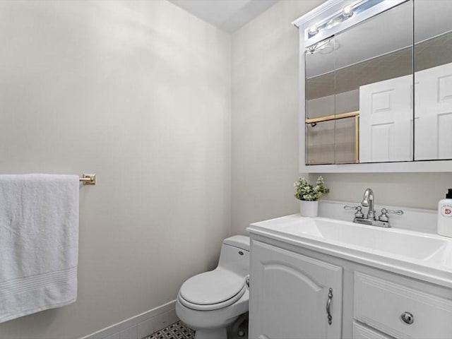 bathroom featuring toilet, vanity, and baseboards