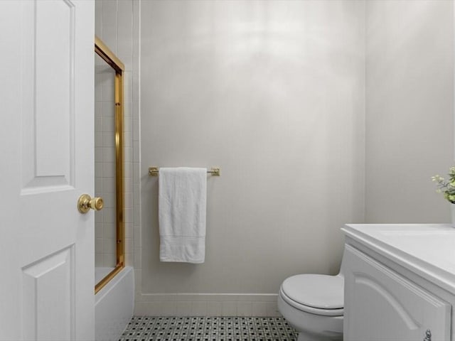 bathroom featuring toilet, vanity, baseboards, and shower / bath combination with glass door