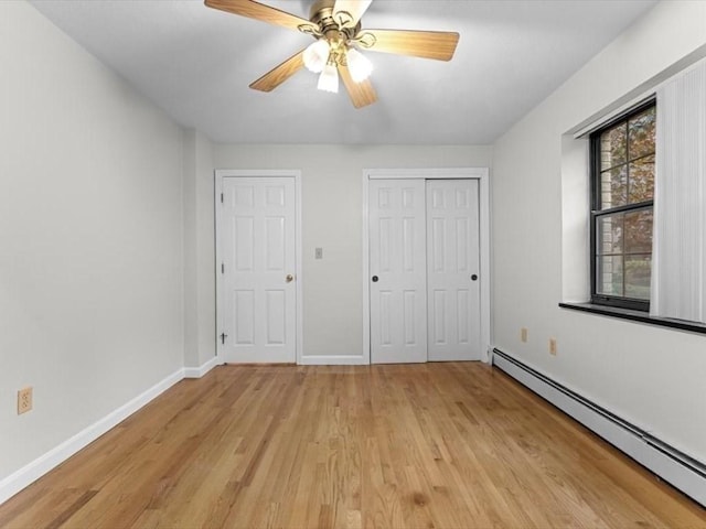 unfurnished bedroom with baseboard heating, light wood-style flooring, baseboards, a closet, and ceiling fan