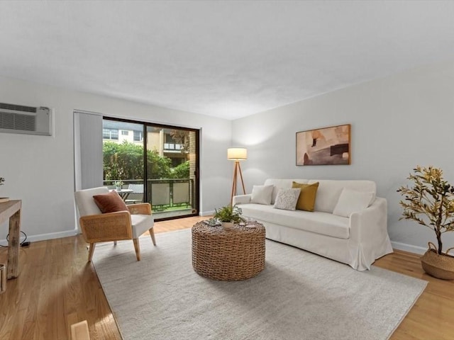 living area featuring a wall unit AC, light wood-type flooring, and baseboards