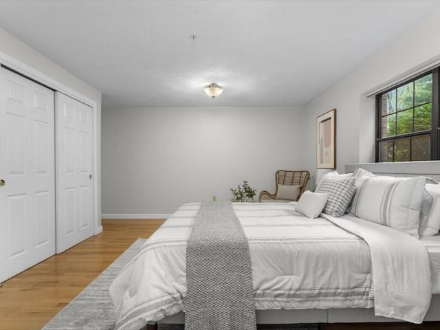 bedroom with wood finished floors, a closet, and baseboards