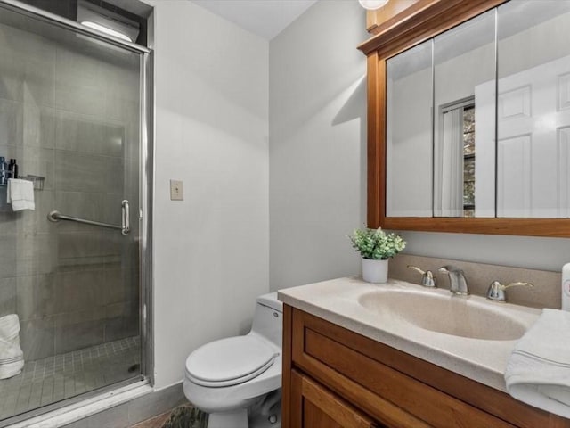 bathroom featuring toilet, a stall shower, and vanity