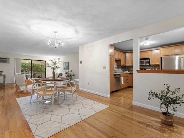 dining room with a chandelier, light wood-type flooring, baseboards, and a wall mounted air conditioner