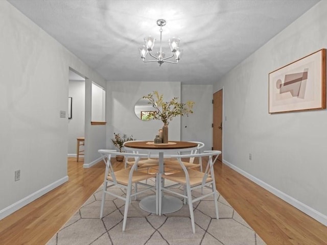 dining area with a chandelier, light wood-type flooring, and baseboards
