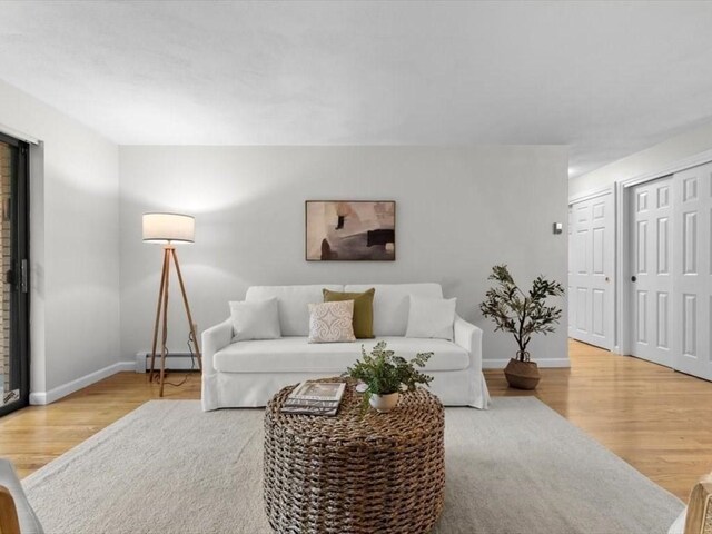 living area featuring baseboard heating, baseboards, and wood finished floors