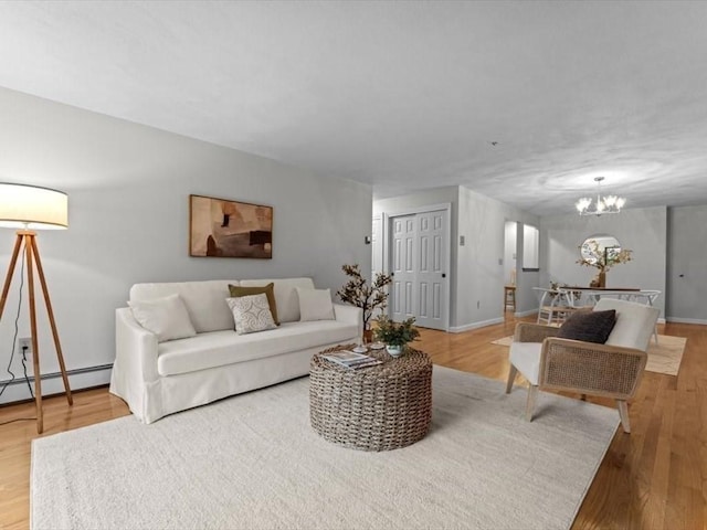 living area featuring a chandelier, wood finished floors, baseboards, and a baseboard radiator