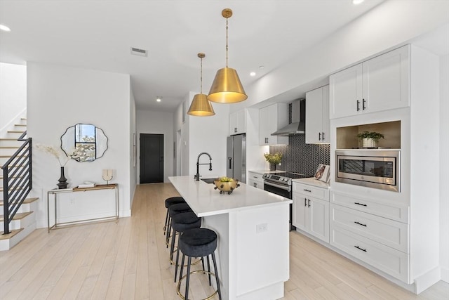 7 Wordsworth Unit Ph6, Boston, MA 02128 - kitchen with stainless steel appliances, wall chimney exhaust hood, a center island with sink, light countertops, and decorative backsplash