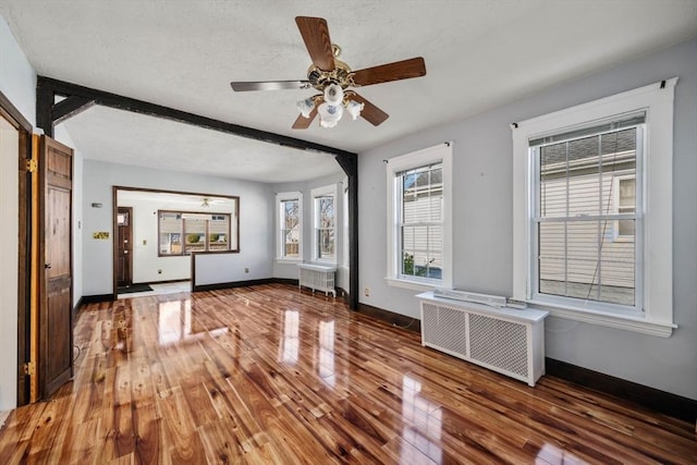 interior space featuring radiator, hardwood / wood-style floors, and beam ceiling