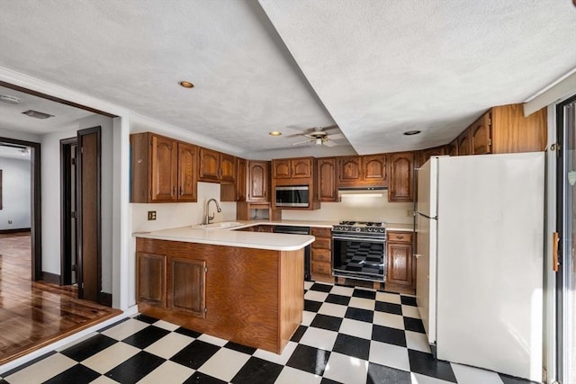 kitchen featuring sink, exhaust hood, ceiling fan, stainless steel appliances, and a textured ceiling