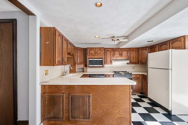 kitchen featuring ceiling fan, appliances with stainless steel finishes, kitchen peninsula, and sink