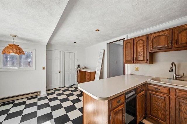 kitchen with decorative light fixtures, sink, a baseboard heating unit, kitchen peninsula, and a textured ceiling