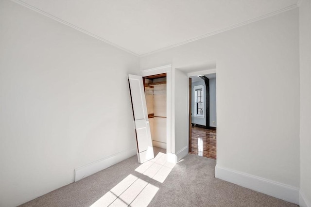 unfurnished bedroom with light colored carpet, ornamental molding, and a closet