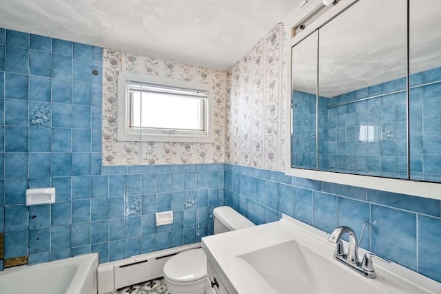 bathroom with a tub to relax in, toilet, tile walls, vanity, and a baseboard heating unit