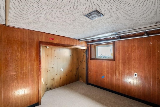 basement featuring wooden walls and carpet floors