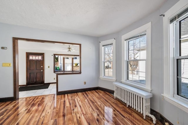 foyer entrance with plenty of natural light, radiator, a textured ceiling, and light wood-type flooring