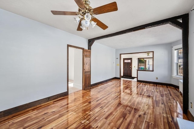 spare room with ceiling fan, wood-type flooring, and beam ceiling