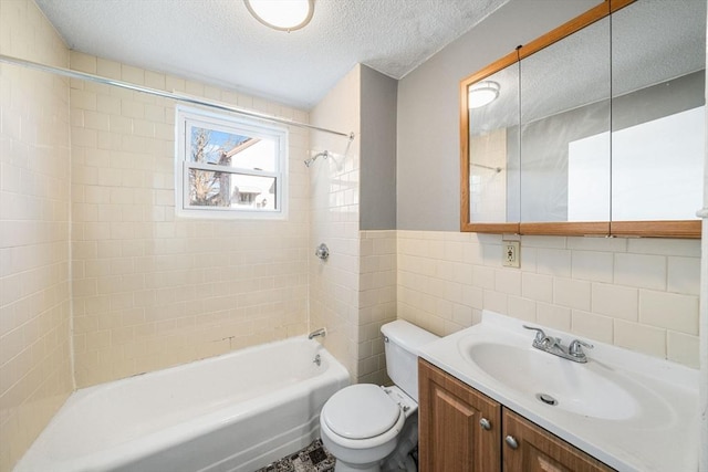 full bathroom with vanity, tiled shower / bath combo, toilet, a textured ceiling, and tile walls