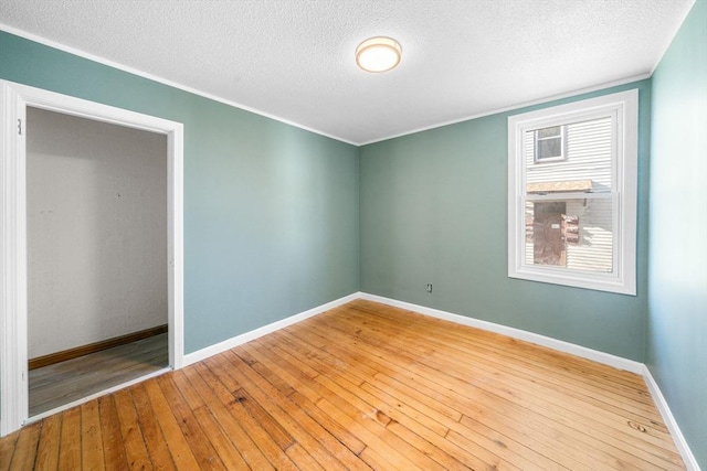 unfurnished room with crown molding, a textured ceiling, and hardwood / wood-style flooring