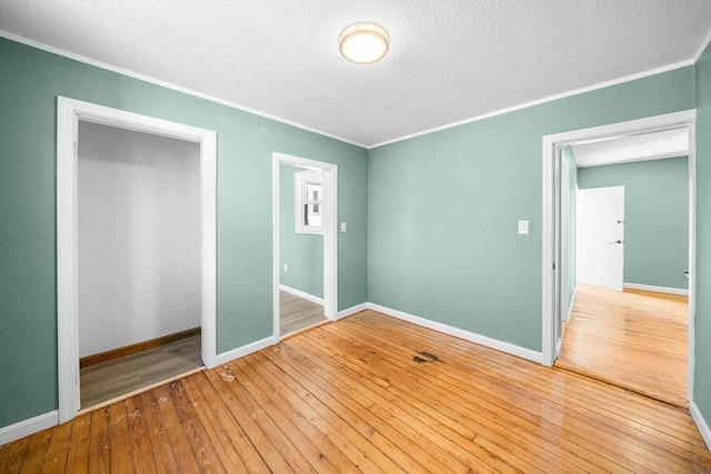 unfurnished bedroom featuring hardwood / wood-style floors, a textured ceiling, and ornamental molding