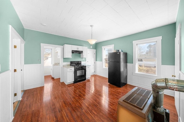 kitchen with black appliances, white cabinets, dark hardwood / wood-style floors, decorative light fixtures, and light stone counters