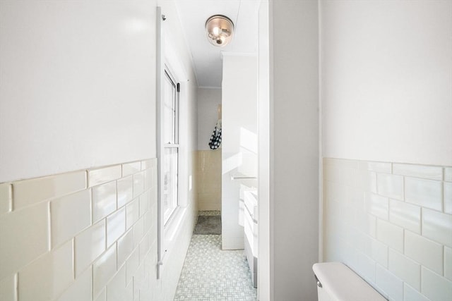 bathroom with tile patterned flooring, toilet, and tile walls