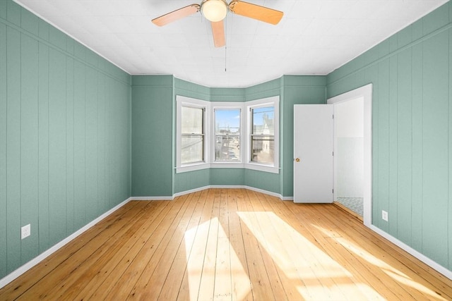 unfurnished room with wood walls, hardwood / wood-style floors, and ceiling fan